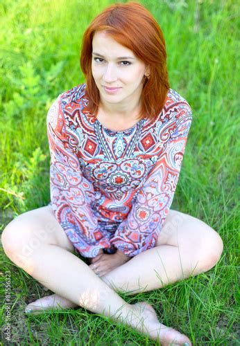 Girl In A Dress With Open Legs Sitting On The Grass Stock Photo And