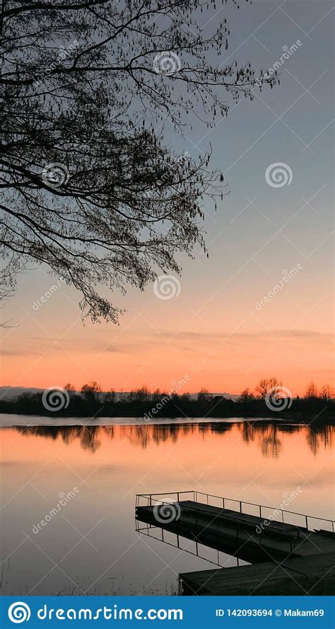 Red Sunset Over The Water Of A Village Lake Stock Photo