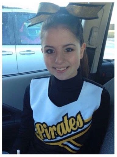 A Girl Sitting In The Back Seat Of A Car Wearing A Cheerleader Shirt