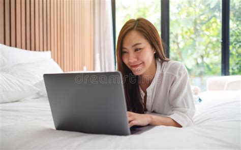 A Beautiful Woman Using And Working On Laptop Computer While Lying Down