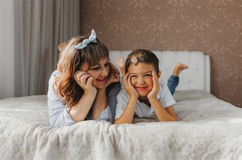 Premium Photo Happy Son And Mom Lie On The Bed And Laugh Mothers Day