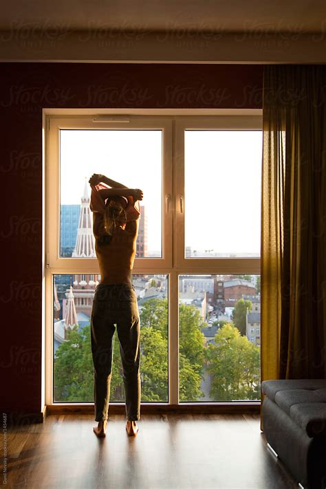 Woman Undressing In Front Of Window By Stocksy Contributor Danil