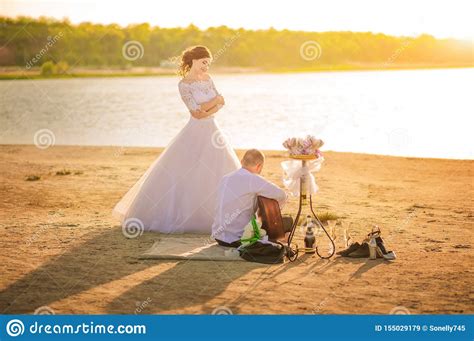 Romantic Wedding Couple At Sunset On The Shore With A Guitar. The Bride And Groom Near The Shore ...