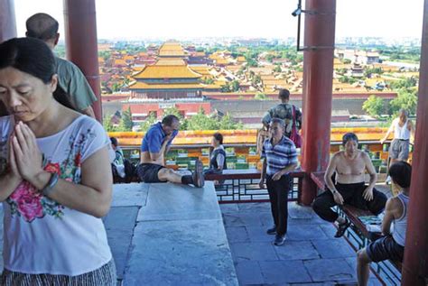 People Exercise As A Woman Prays At Jingshan Park Near The