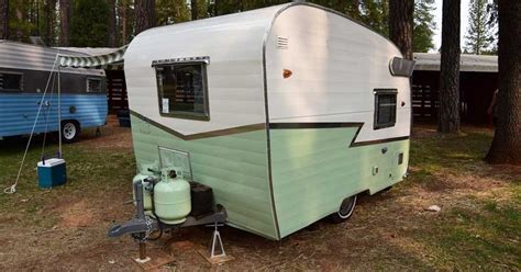 An Old Camper Trailer Is Parked In The Woods Next To Two Other Rvs
