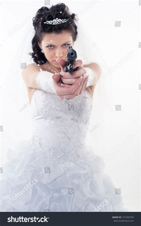 Young Woman In A Wedding Dress With Gun On A White Backgrounda Bride