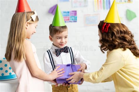 Kids In Party Caps Giving T Box To Boy During Birthday Party At Home