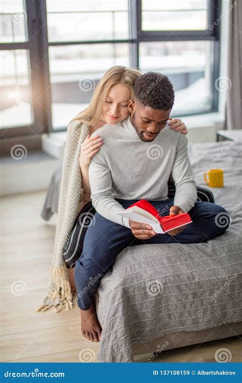 Happy Interracial Couple Spending Weekend Together At Home Relaxing With Book Stock Image