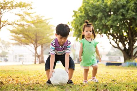 Boy And Girl Learning Kick Ball At The Park In The Evening Stock Photo