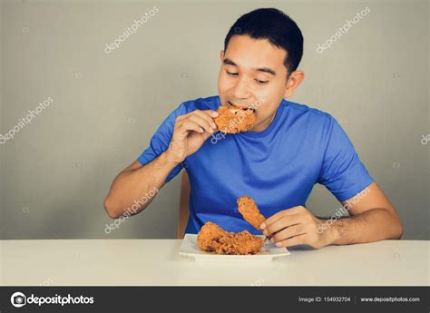 Young Man Eating Fried Chicken On The Table Stock Photo By ©kritchanut