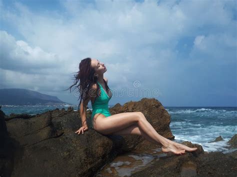 Beautiful Tanned Caucasian Woman Resting On The Rock Sea Beach Crete