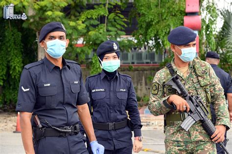 Royal Malaysian Police Officer Aided By Soldiers Manning The Roadblock During Movement Control
