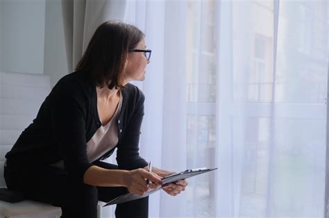 premium photo mature woman social worker psychologist sitting near the window with clipboard