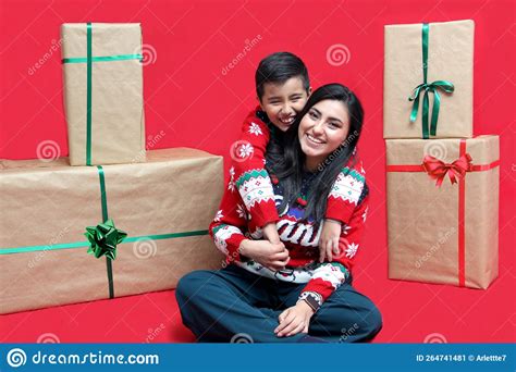 latina mom and son wear ugly christmas sweaters and show their love to each other on a red