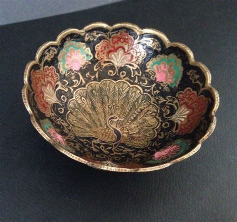 A Decorative Bowl Is Sitting On A Black Table Top With Gold Trimming And Colorful Flowers