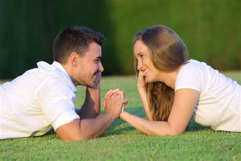Couple Flirting And Looking Each Other Lying On The Grass Stock Photo