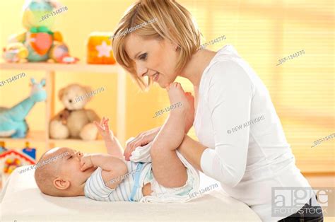 Mother Changing Her Babys Diaper On Nursery Table Stock Photo