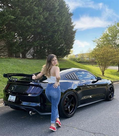 A Woman Standing Next To A Black Sports Car