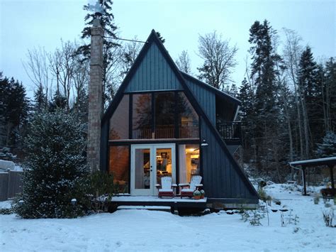 A Small Cabin In The Middle Of Winter With Snow On The Ground And Trees