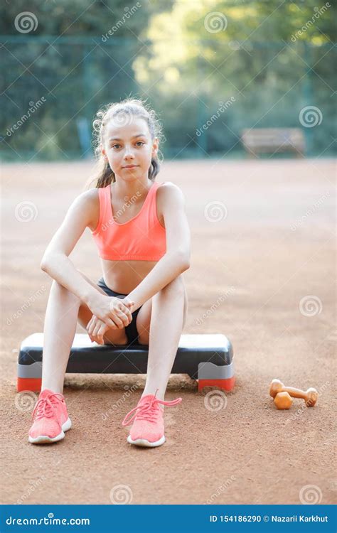 a cute pretty teenage girl sits on a step platform and relaxes after her workout on outdoor