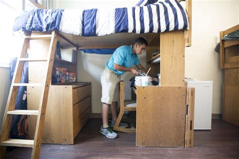 A Man Standing In Front Of A Bunk Bed Next To A Desk With A Laptop On It