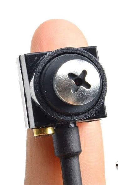 A Hand Holding A Small Black Object With A Button On It