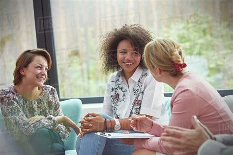 Smiling women talking in group therapy session - Stock Photo - Dissolve