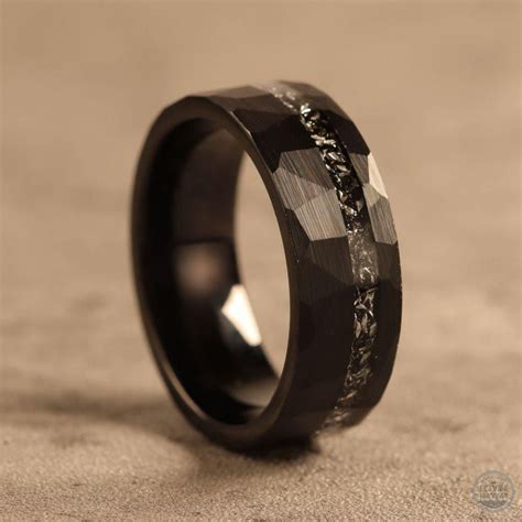A Black Ring With An Intricate Design On The Outside And Inside Sitting On A Surface