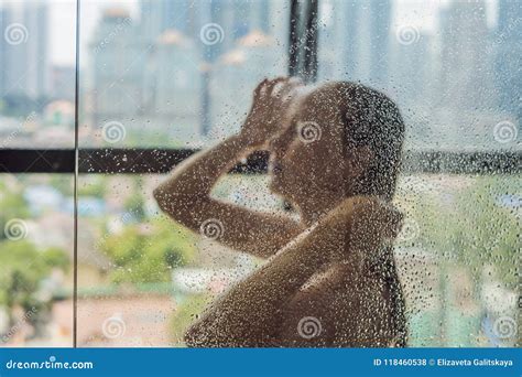Beautiful Woman In The Shower Behind Glass With Drops On The Background Of A Window With A