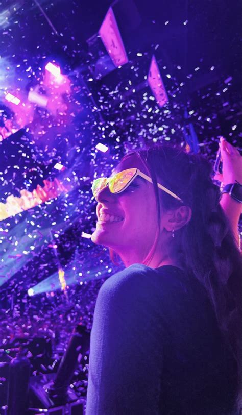 A Woman Wearing Sunglasses And Confetti In Front Of An Audience At A