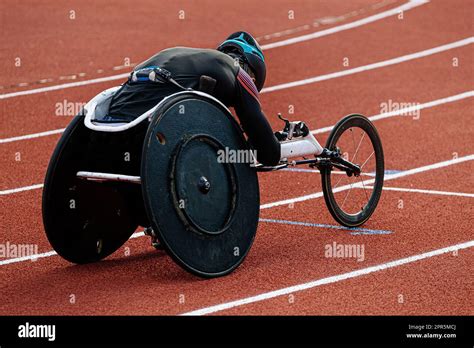 Rear View Para Athlete In Wheelchair Racing Riding On Red Track Stadium