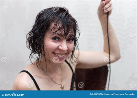 A Brunette Woman With Wet Hair After Shower Stands At The Mirror With Hairdryer Getting Stock