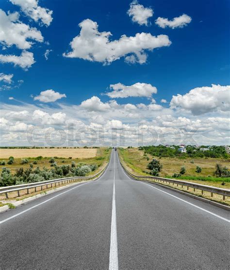 Road With White Central Line Under Deep Blue Sky With Clouds Stock