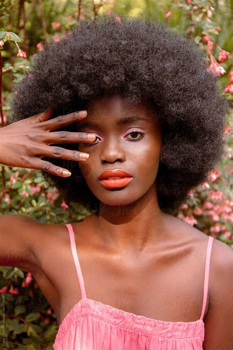 A Woman With An Afro Holding Her Hand Up To Her Face