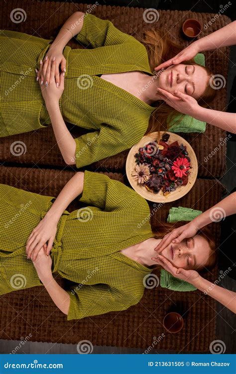 Top View On Two Young Attractive Ladies In Bathrobe Lying On Bed Enjoying Spa Massage Stock