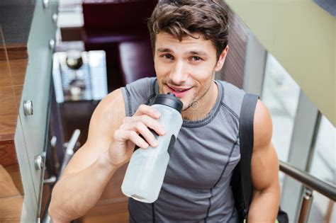 Smiling Man Athlete Walking And Drinking Water In Gym Stock Image
