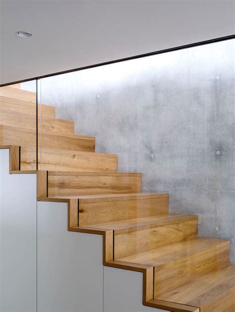 Wood Stairs Sandwiched Between A Concrete Wall And Glass Safety Railing