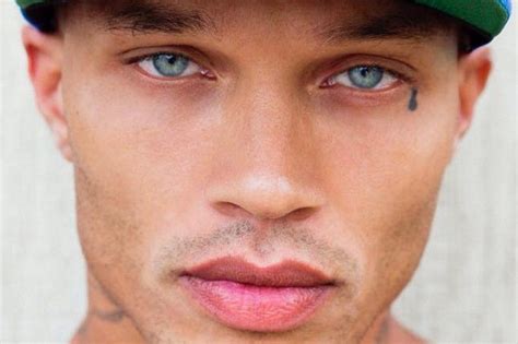 a close up of a person wearing a baseball cap with tattoos on his face and chest