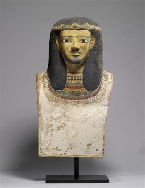 An Ancient Egyptian Mask Is Displayed On A Stand
