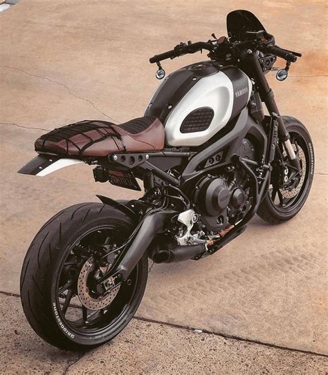 A White And Black Motorcycle Parked On Top Of A Cement Floor Next To A
