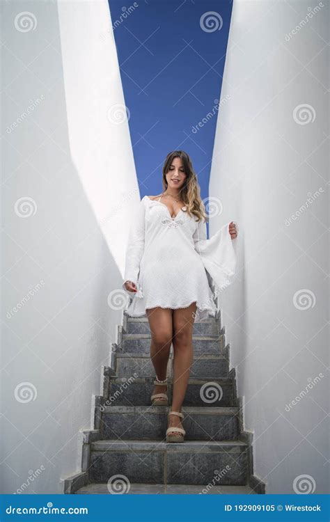 Portrait Of A Female Wearing A White Dress Walking Down On The Stairs