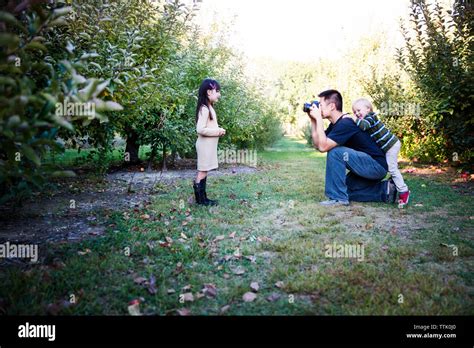 Father Photographing Daughter In Apple Orchard Stock Photo Alamy