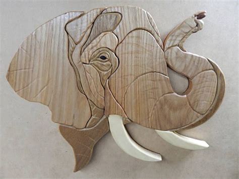 An Elephant Head Made Out Of Wood With White Tusks