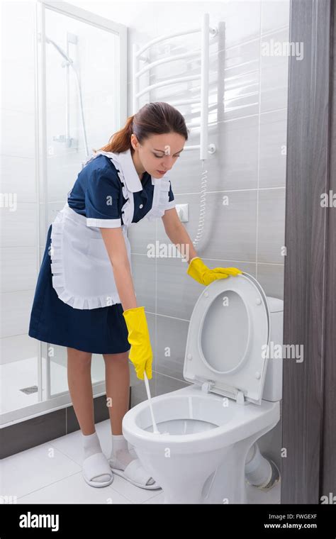 Attractive Housekeeper Cleaning Out A Toilet Standing Scrubbing The