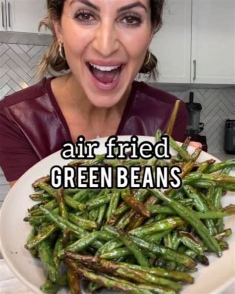 A Woman Holding A Plate Full Of Green Beans With The Caption Air Fried Green Beans