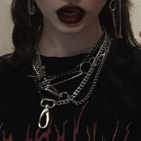 A Woman With Black Lipstick And Chains On Her Neck Holding A Cell Phone