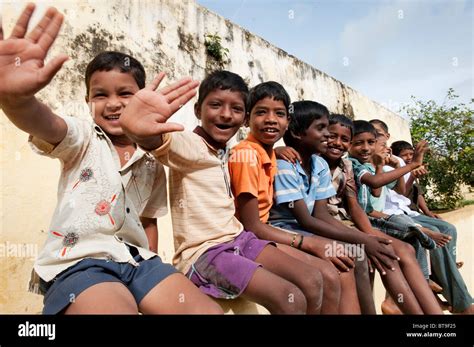 Rural Indian Village Boys Sitting On A School Wall Waving In Bright