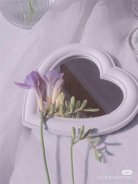 There Is A Heart Shaped Mirror With Flowers In The Center And Two Stems