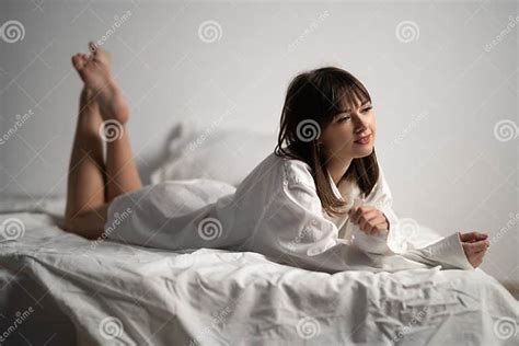 Brunette With Long Legs In A Manand X27s Shirt Resting On The Bed Stock