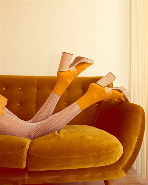 a woman laying on top of a couch wearing yellow stockings and high heeled shoes
